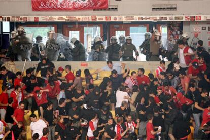 Los seguidores del Olympiakos huyen de la policía antidisturbios durante el partido.