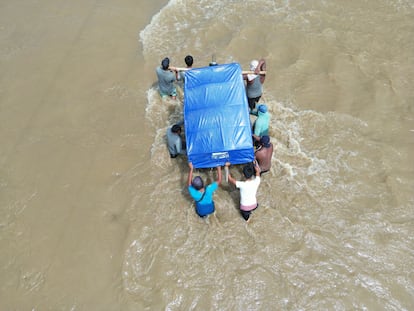 Un mototaxi es llevado en medio de las aguas por ocho hombres. Se trata de una herramienta de trabajo que, al perderse, puede hundir más la vida de algunas familias.