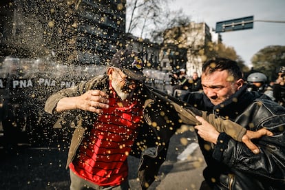 Un manifestante toma a otro del hombro frente al grupo de la Policía Federal Argentina.