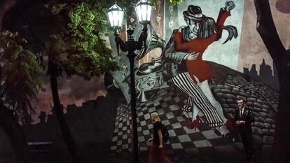 Un hombre pasa por una escena de baile de tango en un mural con una estatua de Roberto Goyeneche, un famoso artista de tango de una época pasada en el barrio de San Telmo, en Buenos Aires (Argentina).