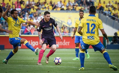 Los jugadores de Las Palmas, Michel Macero y Montoro, defienden al delantero del Barcelona Messi.