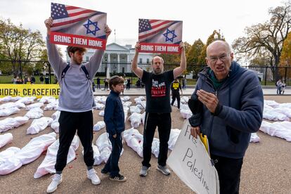 A family visiting from New Jersey holding up posters in support of bringing Israeli hostages home, clashes with a pro-Palestine supporter, right, in front of a large banner that says "Biden: Ceasefire Now" along with fake white body bags, representing those killed in the escalating conflict in Gaza and Israel, is displayed in front of the White House, Wednesday, Nov. 15, 2023, in Washington.