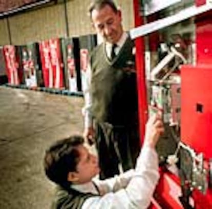 Dos empleados de una empresa de refrescos instalan el monedero electrónico en la máquina de bebidas.