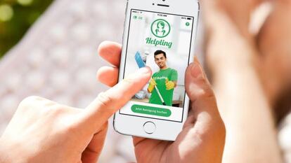 Una persona accede a la app de Helping desde el m&oacute;vil para buscar un profesional de la limpieza.