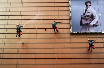 Workers clean the exteriors of a building next to an advertisement in Wuxi, Jiangsu province, China, May 23, 2015. Picture taken May 23, 2015. REUTERS/Stringer/File Photo CHINA OUT. NO COMMERCIAL OR EDITORIAL SALES IN CHINA