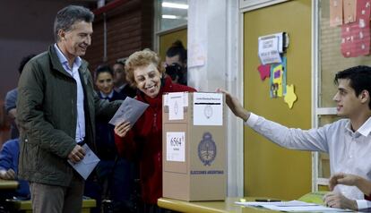 Mauricio Macri, alcalde de la ciudad de Buenos Aires y candidato presidencial, espera que una mujer emita su voto en Buenos Aires.