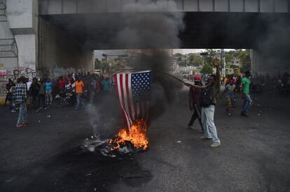 El ministro de Asuntos Exteriores de Haití, Bocchit Edmond, ha informado este lunes de la detención de diez personas -cinco ciudadanos estadounidenses, dos de otras nacionalidades y tres haitianos-- por "conspiración", aunque ha matizado que por el momento no se han presentado cargos formales, según informa la cadena estadounidense de televisión CNN. En la imagen, un manifestante quema una badera estadounidense durante una protesta en Puerto Príncipe, el 15 de febrero.