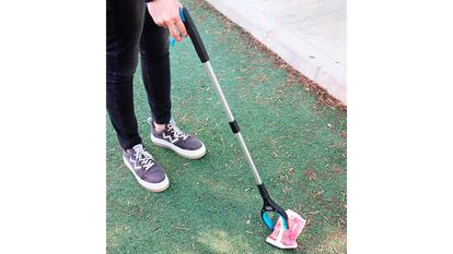 Una persona recogiendo basura con la pinza.