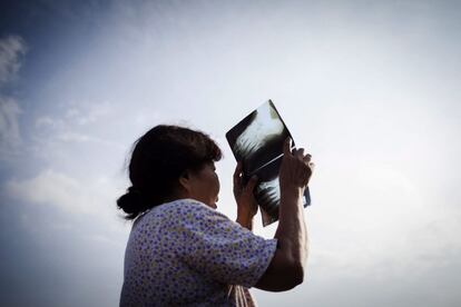 Una dona utilitza una radiografia per veure l'eclipsi de sol a Padang (Indonèsia).