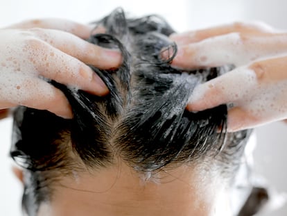 Una persona echándose champú en el cabello