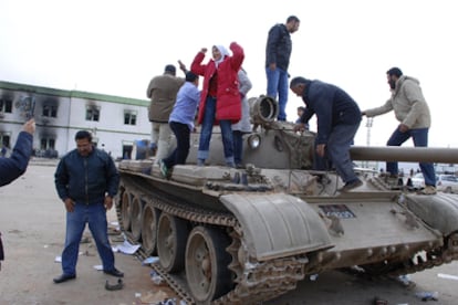Habitantes de Bengasi saltan sobre un tanque ganado al Ejército, en el interior de un complejo militar de la ciudad.