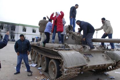 Habitantes de Bengasi saltan sobre un tanque ganado al Ejército, en el interior de un complejo militar de la ciudad.