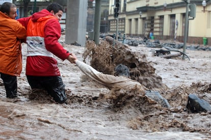 Un hombre es agarrado por otras dos personas para evitar que el agua le arrestre.