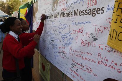 Unos niños escriben mensajes al expresidente sudafricano Nelson Mandela en el exterior del hospital donde se encuentra ingresado, 17 de julio de 2013. Según una encuesta divulgada ayer, nueve de cada diez jóvenes de este país de 50 millones de habitantes dedicarán el 18 de julio 67 minutos de su tiempo a obras de caridad o trabajos para la comunidad.