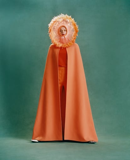 Un sentido del color que coquetea con lo fluorescente define el trabajo de Piccioli para Valentino. Lo demuestra este conjunto de capa, pantalones, top y tocado naranja. Todas las prendas de este reportaje son de la colección de alta costura de otoño-invierno 2022 de Valentino.