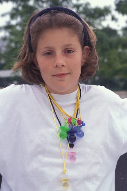 Una niña posa con su colgante repleto de colgantes de chupete en Francia en 1992.