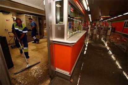 Un operario del metro limpia de agua la taquilla de la estación de Marqués de Vadillo.