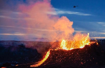 Un helicóptero sobrevuela la lava que fluye de una fisura cerca del Fagradalsfjall en la península de Reykjanes en Islandia. La erupción volcánica, que lleva más de dos semanas en Islandia a unos 40 kilómetros de Reikiavik, se extendió el 5 de abril de 2021 con una nueva fisura que arroja lava.