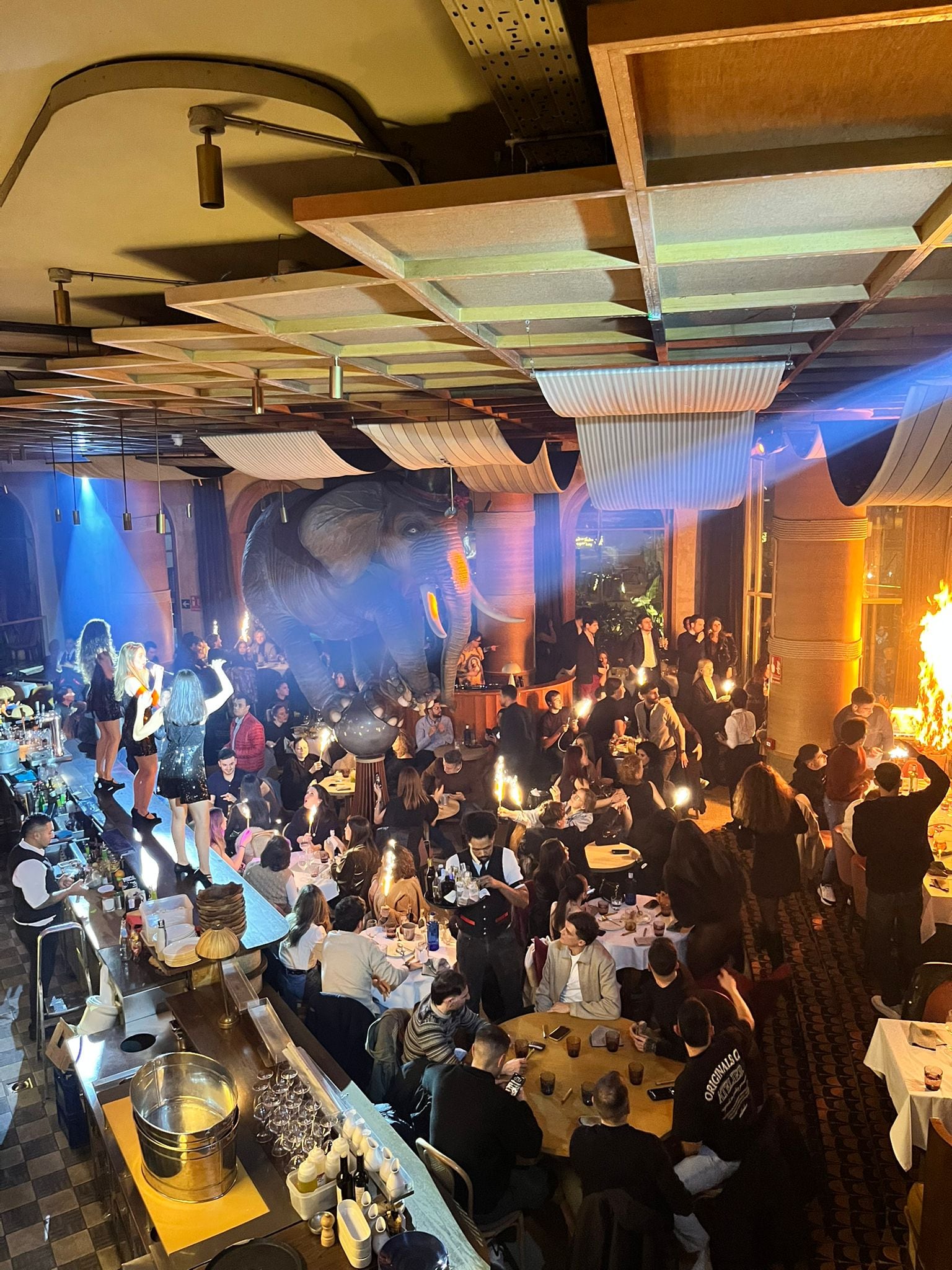 Imagen cedida por una asistente al restaurante Fanático, en Madrid, en la que se ve a tres gogós bailando sobre la barra mientras el público agita las bengalas, en el instante en que se origina el incendio.