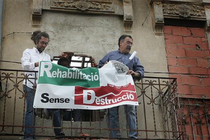 Faustino Villora (derecha) y otro miembro de Salvem El Cabanyal, ayer, colocan una pancarta en uno de los edificios pendiente de derribo.