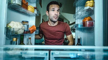 Un hombre abre la puerta de su frigorífico, pero los alimentos no están donde deberían.
