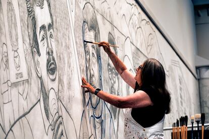 Baca paints an outline of César Chávez in a section of the mural on October 26, 2023.