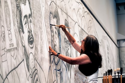 Baca paints an outline of César Chávez in a section of the mural on October 26, 2023.