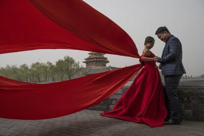 Una pareja durante una sesión de fotos preboda, en el exterior de la Ciudad Prohibida durante una tormenta de arena en Pekín (China).