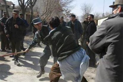 Un policía afgano golpea a un manifestante ayer frente a la Embajada danesa en Kabul.