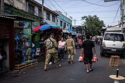 Militares caminan por un mercado callejero en San Salvador.