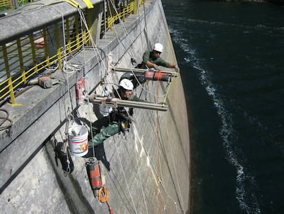 Personal suspendido de HCC realiza perforaciones en una presa.