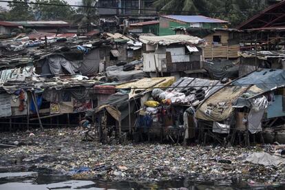 Varios residentes refuerzan los tejados de sus casas utilizando neumáticos pesados en una zona de chabolas en Manila.