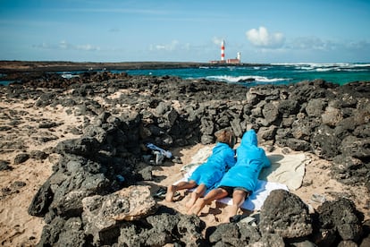 Dos niños observando desde lejos el faro del Tostón, ubicado en El Cotillo (Fuerteventura).