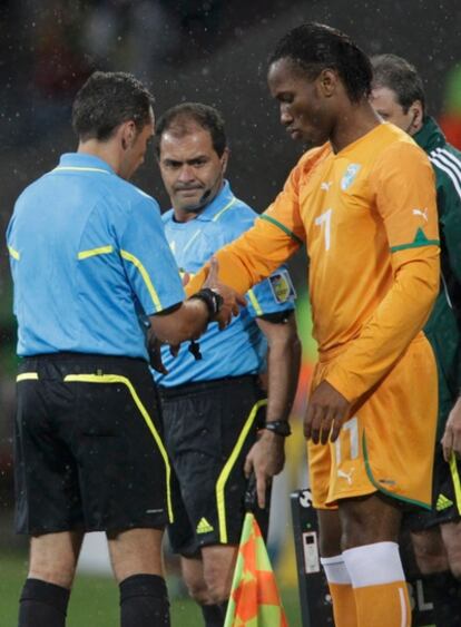 El arbitro hungaro Victor Kassai examina la férula de Drogba antes de que éste entre en el campo.