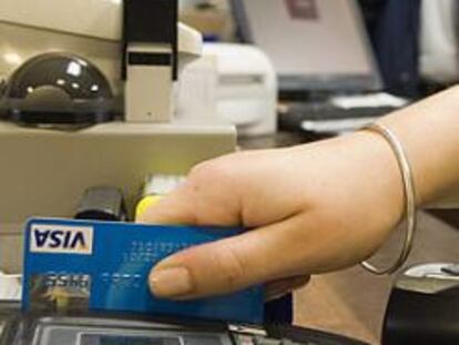 Una dependienta efectúa un cobro con tarjeta de crédito en un establecimiento.