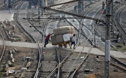 Dos hombres transportan mercanca por las vas del tren de Nueva Delhi (India).