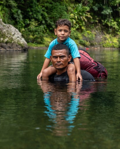 Jonathan "Rambo" Franco crosses the Turquesa River with a four-year-old child on his shoulders.