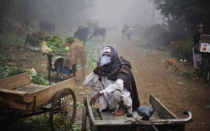 Un trabajador indio, envuelto en una manta, fuma mientras descansa sentado en su `rickshaw´ en Nueva Delhi, India. Delhi y otras partes del noroeste de la India fueron testigos de la primera niebla densa de la temporada.