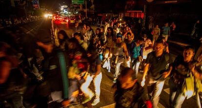 Residents walk the streets of Caracas following Monday's night blackout.