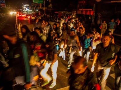 Pedestres caminham em uma rua às escuras, em Caracas.