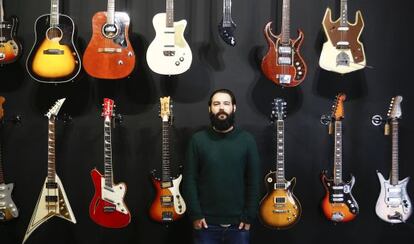 Israel Dom&iacute;nguez ante varias de las guitarras que vende en su tienda.