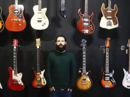 Israel Dom&iacute;nguez ante varias de las guitarras que vende en su tienda.