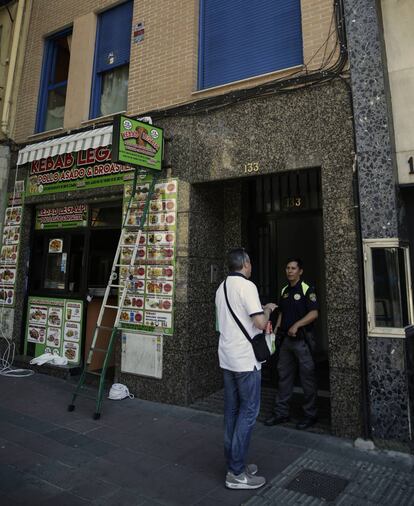 Un agente de seguridad habla con un hombre en el portal del edificio de Paseo de las Delicias, 133.