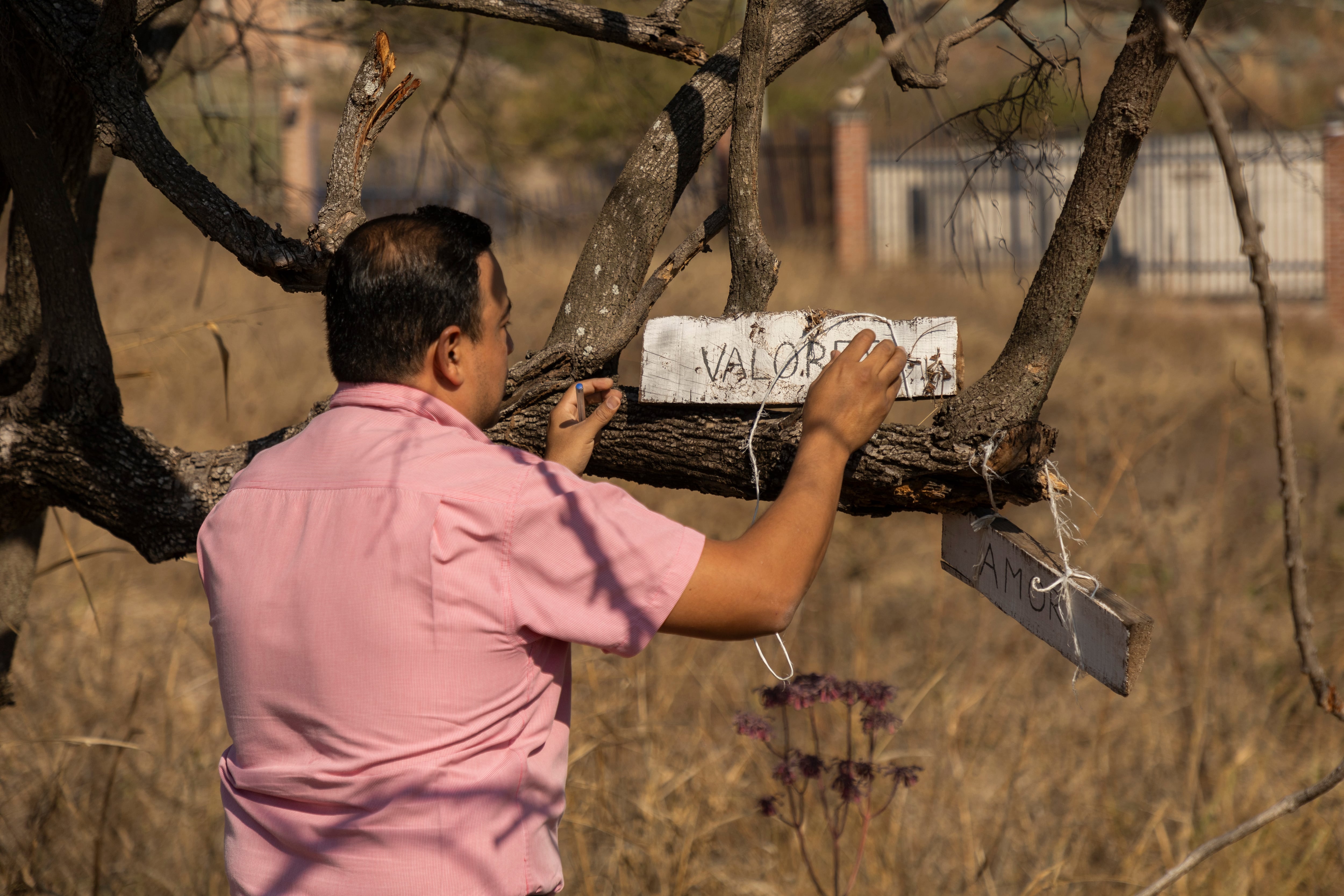 El maestro Alberto González, coordinador de la preparatoria agroecológica El Limón, coloca un letrero en el espacio llamado El Sendero de la Paz, destinado a dar privacidad a los estudiantes.