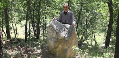 El escultor, Climent Olm, junto a una de las 600 esculturas que ha cincelado en las piedras de su montaña.