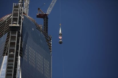 Una gr&uacute;a sube la bandera de EE UU a la cima del One World Trade Center.
 