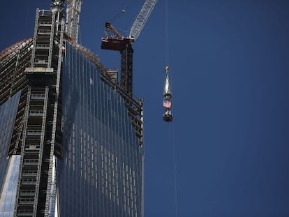 Una gr&uacute;a sube la bandera de EE UU a la cima del One World Trade Center.
 