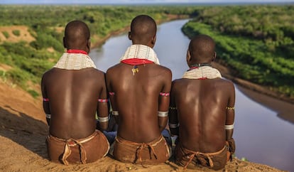 Tres chicos de la etnia karo contemplan el río a su paso por el valle del Omo en Etiopía, en la frontera con Kenia.