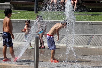 Unos chavales se refrescan en los chorros de agua de la explanada del Guggenheim