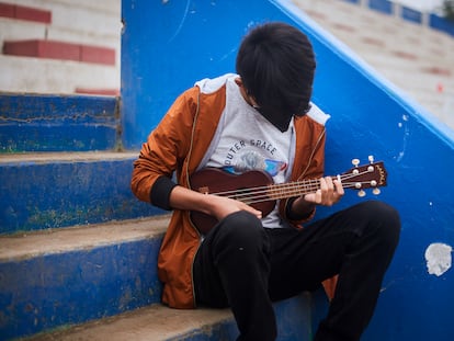 Andre (nombre ficticio), de 14 años, toca el ukelele en las gradas de un estadio deportivo remodelado en Carabayllo, un distrito en el norte de Lima, Perú, mientras espera la hora de su cita programada para ser atendido en el Centro Comunitario de Salud Mental.